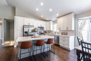 Kitchen with lofted ceiling, decorative backsplash, a sink, and appliances with stainless steel finishes