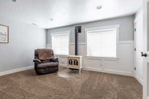 Sitting room with a wood stove, carpet, visible vents, and baseboards