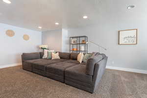 Carpeted living area with recessed lighting, a textured ceiling, and baseboards