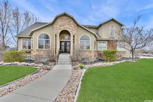 View of front facade featuring french doors, stucco siding, stone siding, and a front yard
