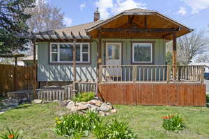 View of front of house featuring a porch, a front yard, fence, a chimney, and a shingled roof
