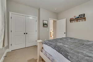 Bedroom featuring a closet, baseboards, and light colored carpet