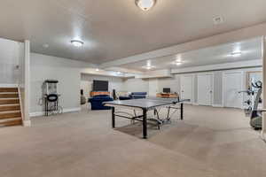 Playroom with a textured ceiling, light colored carpet, baseboards, and visible vents