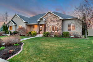 View of front of property featuring stucco siding, a front yard, fence, stone siding, and a shingled roof