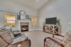 Living area with a wealth of natural light, high vaulted ceiling, carpet, and a tile fireplace
