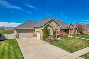 View of front of house featuring concrete driveway, stucco siding, an attached garage, a front yard, and a gate