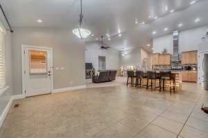 Dining space featuring high vaulted ceiling, light tile patterned floors, a ceiling fan, recessed lighting, and baseboards