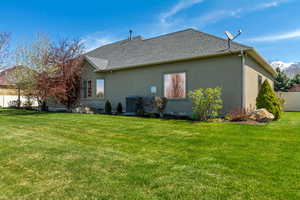 Rear view of house featuring stucco siding, fence, and a lawn