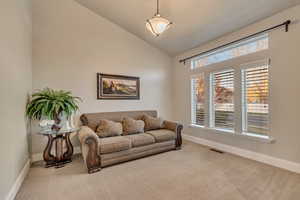 Living area featuring vaulted ceiling, baseboards, carpet, and visible vents