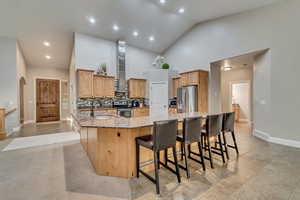 Kitchen with stone counters, high vaulted ceiling, wall chimney exhaust hood, stainless steel appliances, and a sink