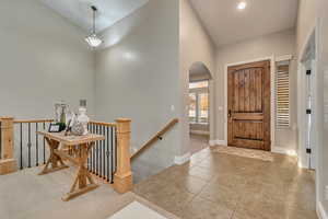 Tiled foyer with baseboards, arched walkways, and vaulted ceiling