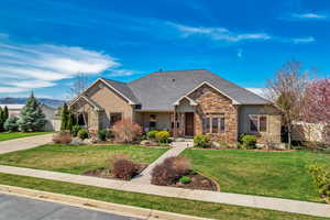 View of front facade with a front yard, stone siding, and stucco siding