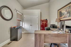 Office area featuring light colored carpet, baseboards, lofted ceiling, and visible vents
