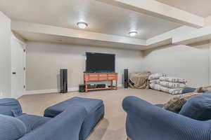 Living room with carpet floors, baseboards, and a textured ceiling