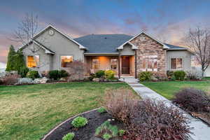 View of front of home featuring stucco siding, stone siding, and a front yard