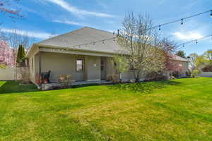 Back of house with stucco siding, fence, and a lawn