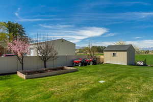 View of yard featuring a shed, a fenced backyard, an outdoor structure, and a vegetable garden