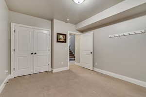 Unfurnished bedroom with a closet, baseboards, light colored carpet, and a textured ceiling