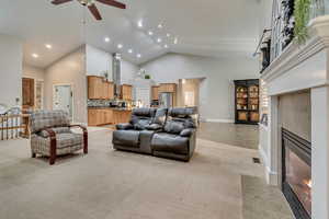 Living room featuring a fireplace, recessed lighting, ceiling fan, high vaulted ceiling, and light colored carpet