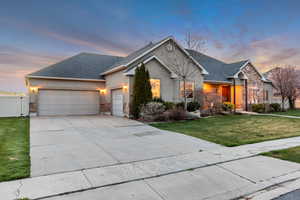 Ranch-style home featuring a yard, a garage, stucco siding, and stone siding