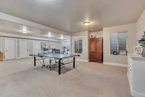 Game room featuring light carpet, baseboards, visible vents, and a textured ceiling