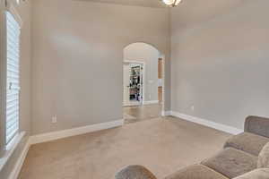Living room with baseboards, arched walkways, a high ceiling, and light carpet