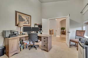 Office space with arched walkways, a high ceiling, and light carpet