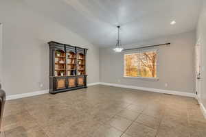 Unfurnished dining area with light tile patterned floors, baseboards, and vaulted ceiling