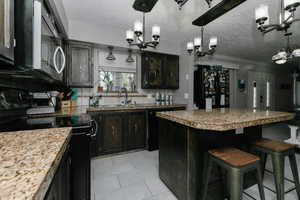 Kitchen with a chandelier, a sink, backsplash, and black appliances