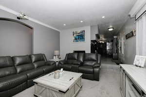 Living area with a textured ceiling, recessed lighting, light carpet, and arched walkways