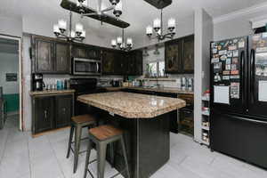 Kitchen with a chandelier, a textured ceiling, a sink, and black appliances