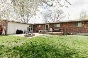 Back of property featuring a patio area, brick siding, crawl space, and a lawn