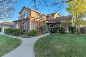 Traditional-style home featuring stucco siding, fence, a front lawn, and a balcony