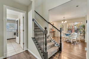 Stairway featuring washer and dryer, a healthy amount of sunlight, wood finished floors, and a chandelier