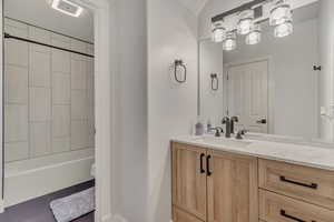 Bathroom featuring vanity, baseboards, and  shower combination