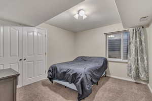 Carpeted bedroom featuring a textured ceiling, a closet, and baseboards