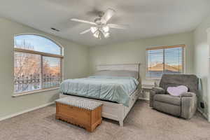 Bedroom featuring baseboards, multiple windows, light colored carpet, and a ceiling fan