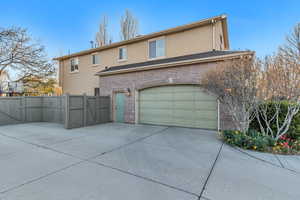 Back of property featuring fence, a gate, driveway, and stucco siding