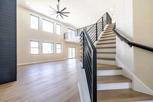 Stairway featuring baseboards, recessed lighting, a high ceiling, and wood finished floors