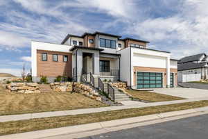 Modern home with concrete driveway, a garage, stucco siding, and stairs