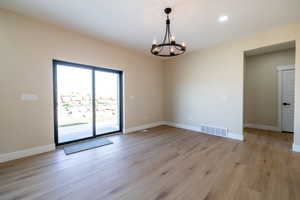 Unfurnished room featuring visible vents, baseboards, an inviting chandelier, and light wood-style flooring