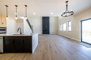 Kitchen featuring a sink, light countertops, light wood-style floors, and a fireplace
