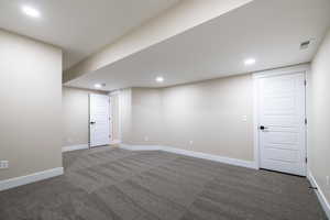 Finished below grade area with visible vents, baseboards, recessed lighting, and carpet flooring