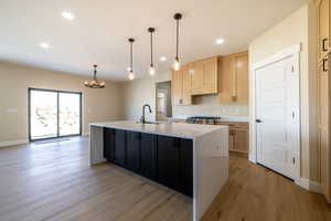 Kitchen with a notable chandelier, a sink, light countertops, light brown cabinetry, and light wood finished floors