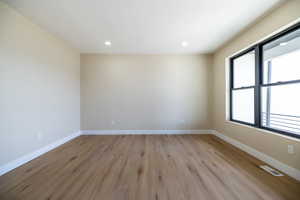 Empty room with visible vents, baseboards, light wood finished floors, and plenty of natural light