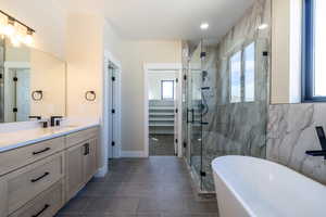 Full bath featuring baseboards, a freestanding tub, vanity, tile patterned flooring, and a stall shower
