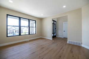 Empty room featuring visible vents, baseboards, light wood-type flooring, and recessed lighting