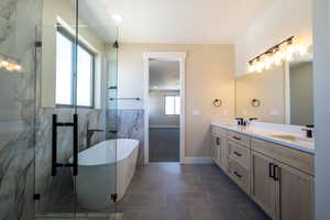 Full bathroom featuring double vanity, a soaking tub, tile patterned floors, a marble finish shower, and a sink