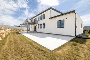 Back of property featuring a patio, a balcony, stucco siding, a yard, and fence