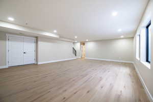 Basement with recessed lighting, light wood-style flooring, baseboards, and stairs